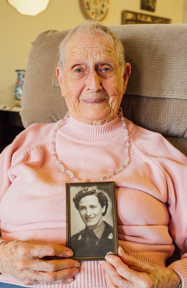 madeline shavalier holding a picture of herself as a nurse in WWII